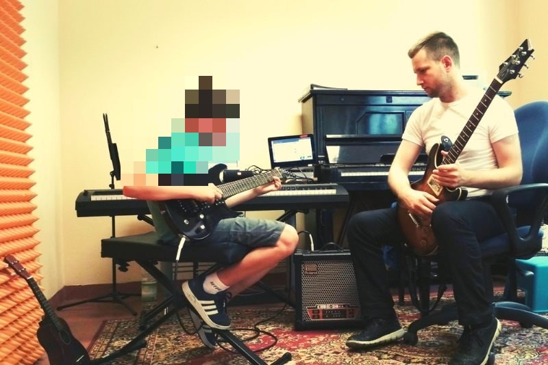 Michał Drezner gra na gitarze razem z nastolatkiem podczas zajęć